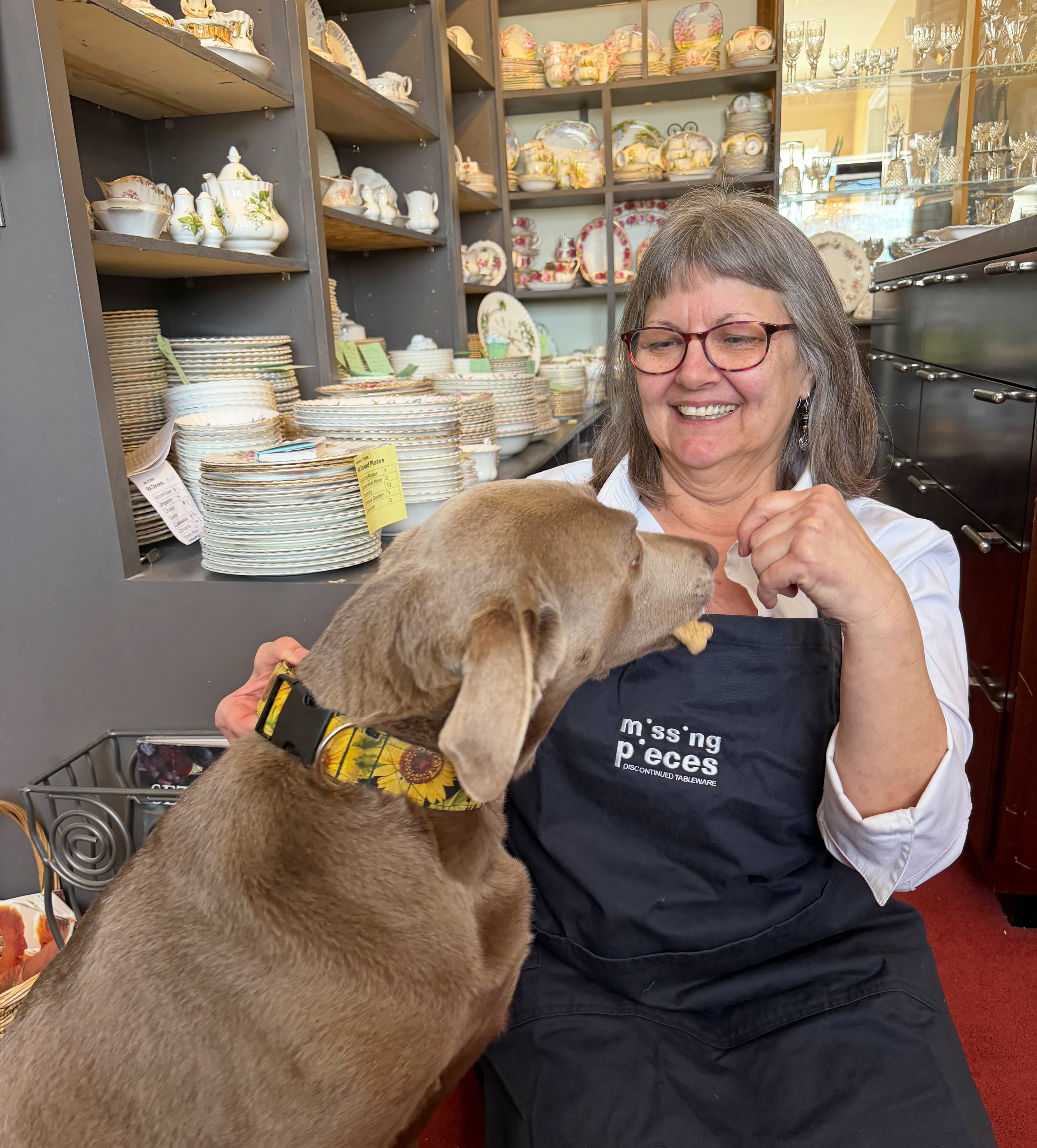 Janice smiling in her Missing Pieces shop surrounded by collectible china